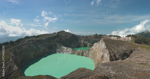 Tourist woman enjoy morning view on volcanic Kelimutu blue crater lakes. Nature background. Travel destination. Beautiful wild landscape. Exotic summer vacation, hiking, relax. Close up back view 4K photo