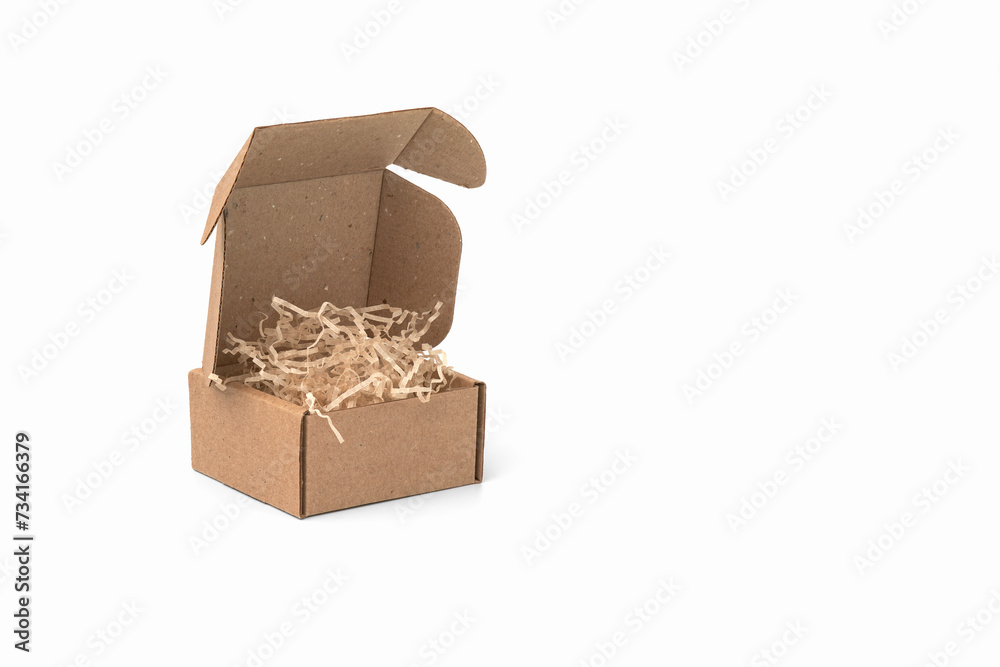 Cardboard box with kraft paper filling on white background. Copy space. Cardboard box with kraft paper filling on white background. Copy space.