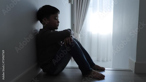 The child is sitting sadly in the house.