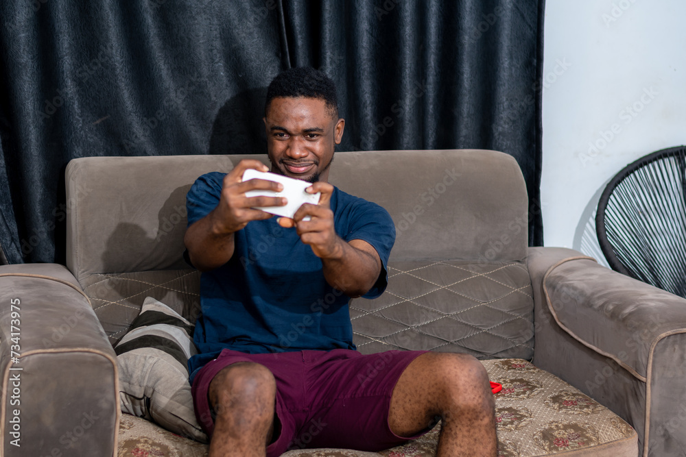 Young excited African-american guy playing game on his mobile phone Young excited African-american guy playing game on his mobile phone