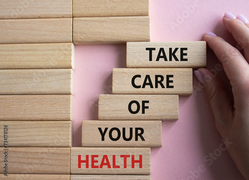 Health symbol. Wooden blocks with words Take Care of your Health. Doctor hand. Beautiful pink background. Health concept. Copy space.