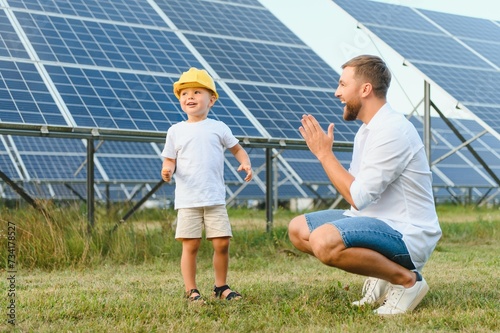 A father and his little son near the solar panels. A little boy in a yellow helmet