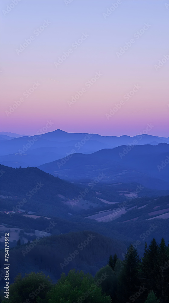 Sunset in the mountains, landscape at twilight with layers of hills and a gradient sky from blue to pink hues