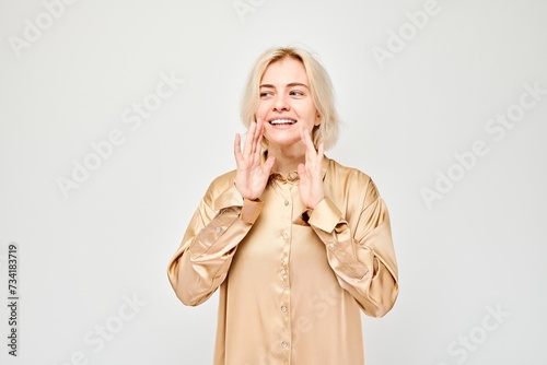 Portrait of blonde girl shouting loudly with hands  news  palms folded like megaphone isolated on white background