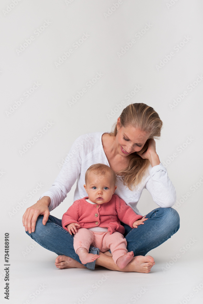Mother sitting on the floor looking down to baby on her lap Mother sitting on the floor looking down to baby on her lap