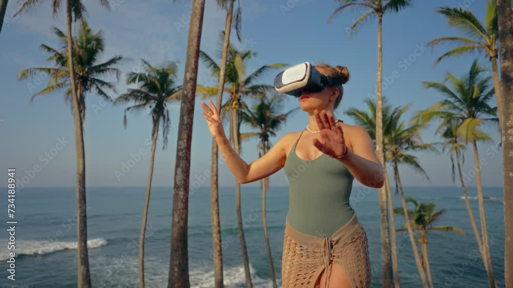 Woman in VR headset explores virtual realm among palm trees by ocean