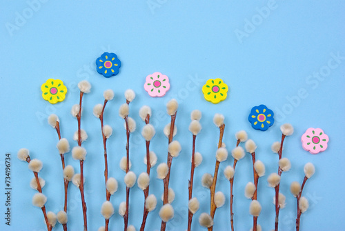 Easter decoration with pussywillow twigs and wooden painted flowers on blue background for greeting card or poster © Agata