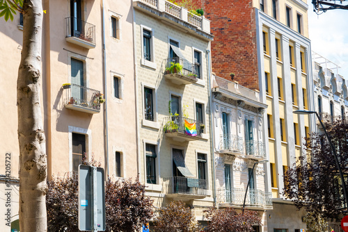 Beautiful Spainish balcony with rainbow flag and much flowers in summer city. photo