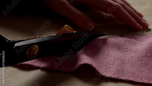 Tailor's Scissors Cutting Through Red Fabric. Dark tailor scissors slice vibrant red felt on crafting table. photo