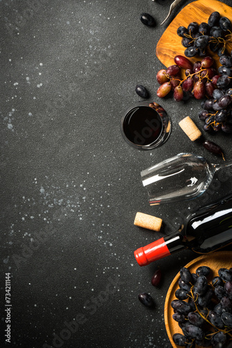 Red Wine at black background. Glass of wine, bottle, crape and corkscrew. Top view with copy space.