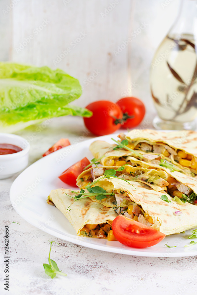 Mexican Quesadilla wrap with chicken, corn and sweet pepper on white plate.