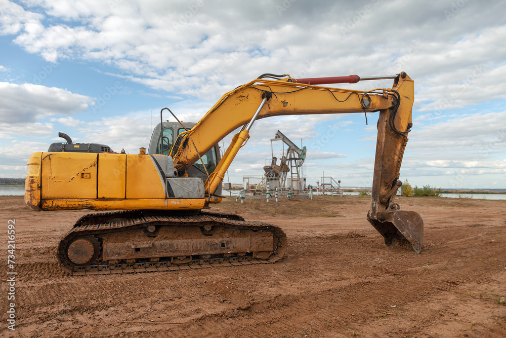 crawler excavator stands on background of an oil pump during the day, special equipment crawler excavator stands on background of an oil pump during the day, special equipment