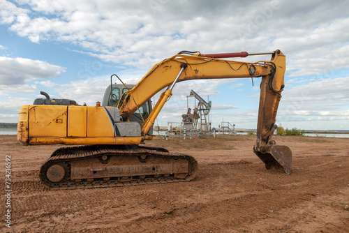 crawler excavator stands on background of an oil pump during the day  special equipment