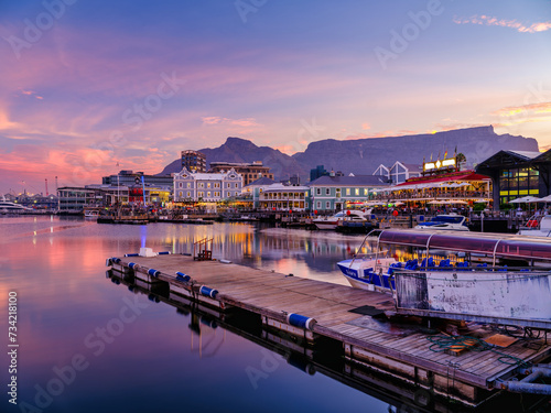 Victoria and Alfred, V and A waterfront lit up during a colorful sunset  with table mountain in the background, Cape Town, South Africa