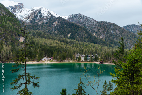 Aerial view of alpine lake Lago di Braies with lakeside hotel in Dolomities mountains, Belluno, Veneto, Italy on moody spring day. Lake in the forest in Dolomiti in Italian Alps