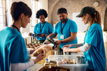 Multiracial group of volunteers packing groceries at community food bank.