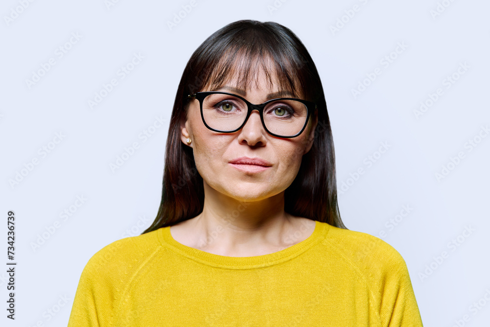 Headshot portrait of serious mature woman on white studio background