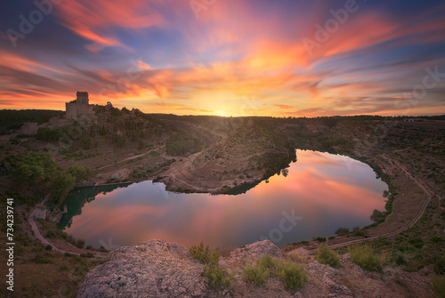View of a colorful sunset from the Alarcon viewpoint, Cuenca, with the warm clouds reflecting in the Jucar River photo