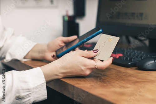 Woman's hands holding credit card and using mobile phone and pc on a table for online shopping, payment or working