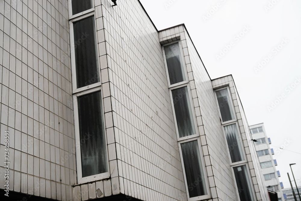 Weiße Klinkerfassade mit drei Vorbauen mit Fenstern von Tanzschule vor weißem Himmel in Stadt am Mittag im Winter Weiße Klinkerfassade mit drei Vorbauen mit Fenstern von Tanzschule vor weißem Himmel in Stadt am Mittag im Winter
