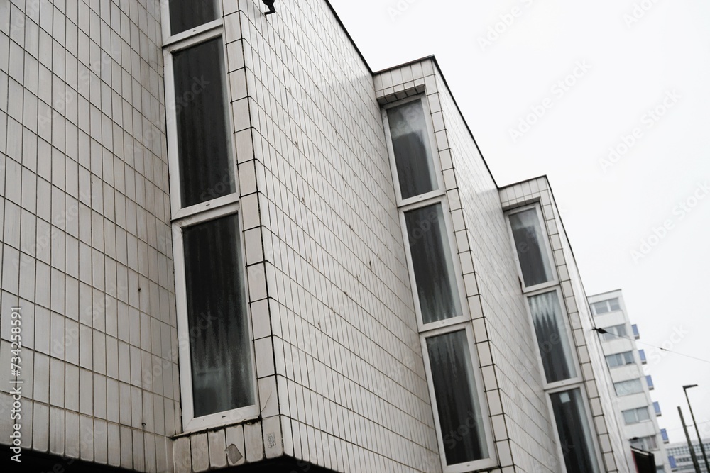 Weiße Klinkerfassade mit drei Vorbauen mit Fenstern von Tanzschule vor weißem Himmel in Stadt am Mittag im Winter