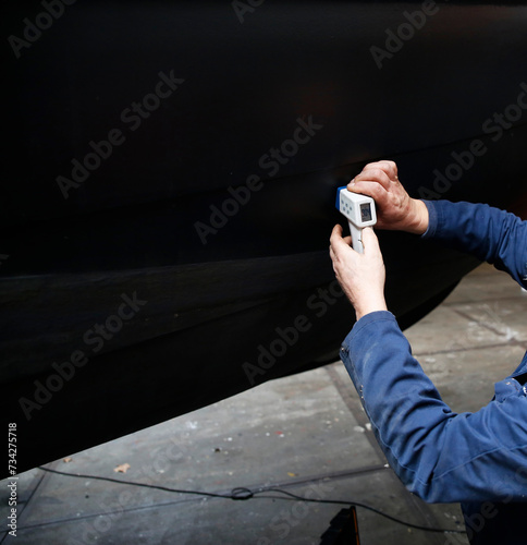 Foto A service engineer measuring the thickness of the steel hull of a boat using an