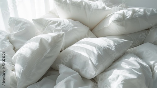  a pile of white pillows sitting on top of a bed covered in white sheets and down comforters with a window in the background.