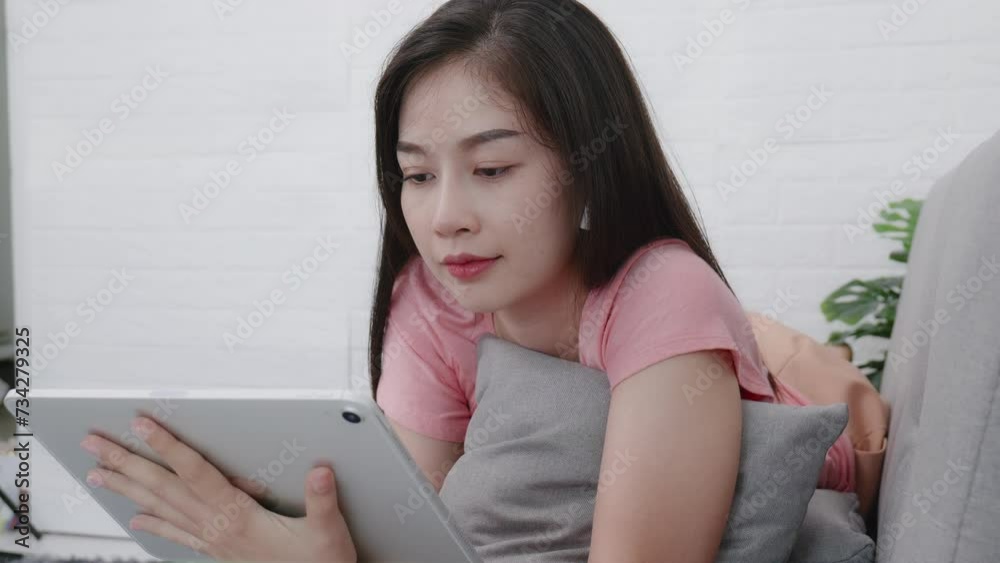 Asian woman using tablet or smartphone to trade stocks in living room Asian woman using tablet or smartphone to trade stocks in living room