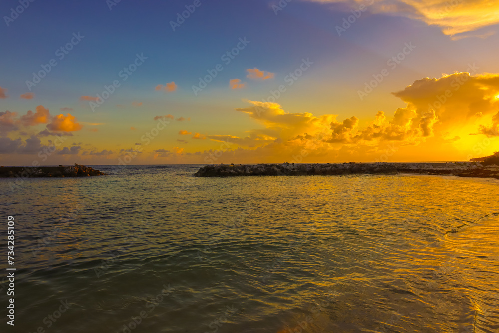 Golden sunset Grand Cayman Cayman Islands by the beach Caribbean sea ocea waves crash against the sand with clouds in the sky dark