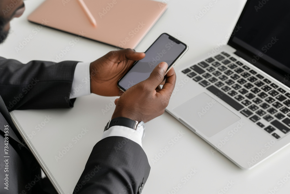 A man in a suit is using a cell phone and a laptop A man in a suit is using a cell phone and a laptop