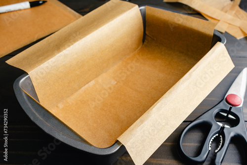 Loaf Pan Lined with Unbleached Parchment Paper: Bread pan lined with trimmed baking paper with scissors and a marker in the background photo