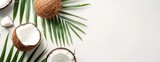 A photo showcasing a fresh whole and half-cut coconut alongside palm leaves on a white background.
