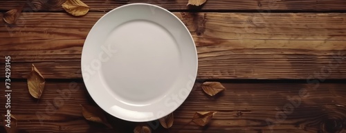 A white plate rests on top of a beautiful wooden table with an autumnal background.