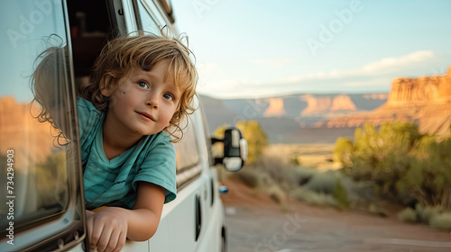 Child looks out of the window of campvan on the road photo