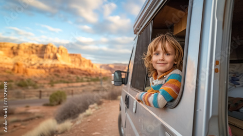 Child looks out of the window of campvan on the road photo