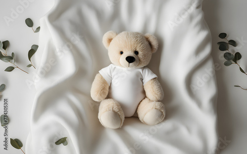 White cotton baby short sleeve bodysuit, toy teddy bear and eucalyptus branch on white ivory blanket throw background. Blank infant onesie mockup template. Top view