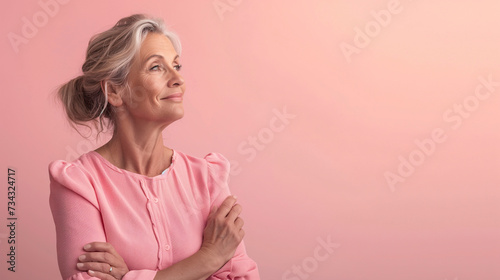 Retrato de mujer madura vestida de color rosa sobre fondo liso de color rosa. 