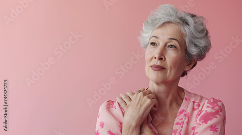 Retrato de mujer madura vestida de color rosa sobre fondo liso de color rosa. 