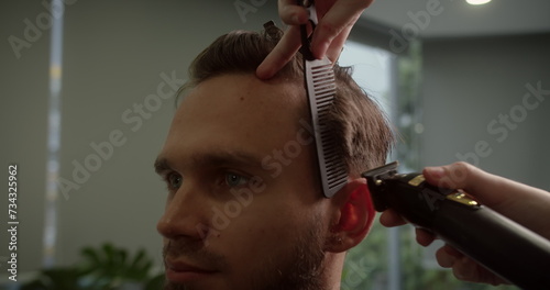 Hairdresser makes a hairstyle with a hair comb and a hair machine. Stylish man sitting barbershop. Hairdresser Woman cutting his hair Portrait handsome young handsome man with trendy hair haircut. 4K