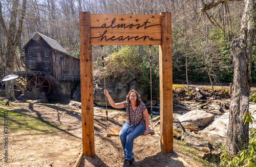 Woman on the Almost Heaven Swing in Front of the Glade Creek Grist Mill and Waterfall in West Virgina During a Sunny Spring Day