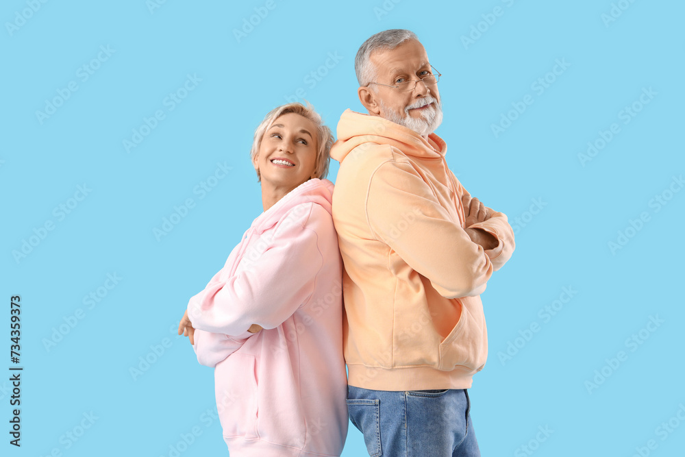 Mature couple in hoodies on blue background Mature couple in hoodies on blue background