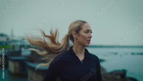 strong young woman running on  beach jogging  exercising cardio workout training focused female athlete runner in cloudy seaside background tracking close up photo