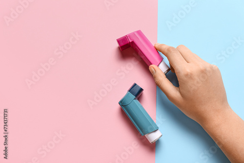 Child's hand with asthma inhalers on color background photo