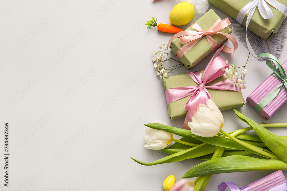 Easter eggs with flowers and gift boxes on grey background Easter eggs with flowers and gift boxes on grey background