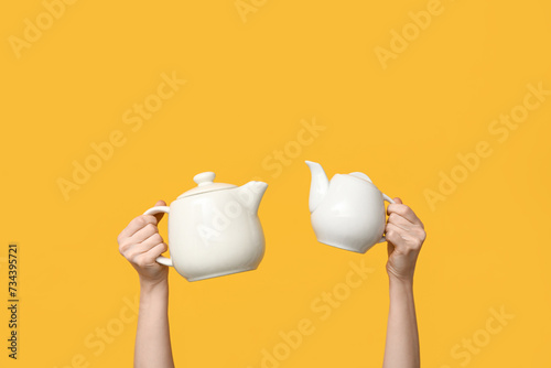 Woman with ceramic teapots on yellow background