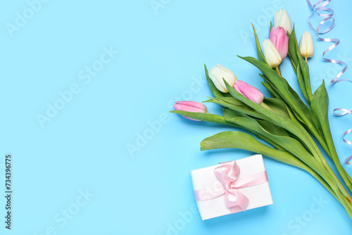 Fototapeta Naklejka Na Ścianę i Meble -  Beautiful tulips and gift box on blue background. International Women's Day