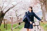春に桜並木を自転車で学校に通う中学生・高校生・女子高生・女子高校生（通学・下校）
