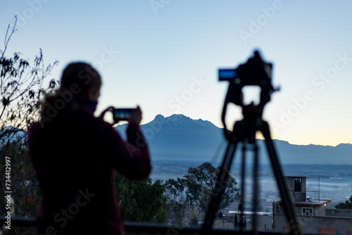 Fotografa esperando, contemplando el solsticio de invierno con los volcanes mexicanos en el amanecer del invierno de diciembre. Iztaccihuatl y Popocatepetl. México.