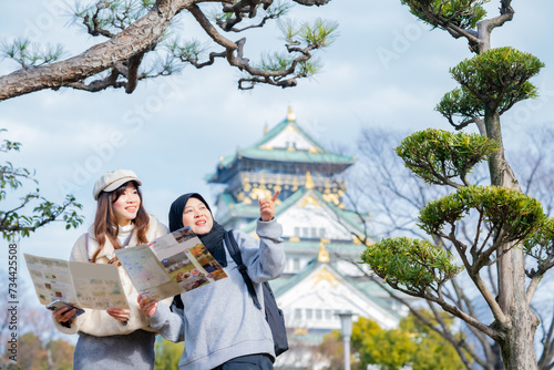Travel  muslim travel  woman girl tourist Two Asian friends but different religions walking and visitor learning about history at Osaka Castle  landmarks in Japan and Osaka  holiday lifestyle.