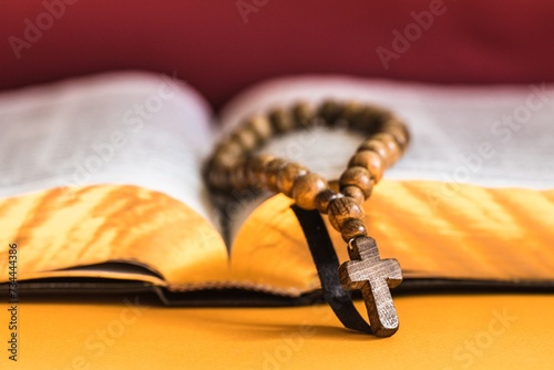 Rosary beads resting on open bible on wooden table